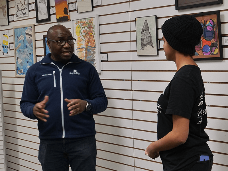 A student talkin to a faculty member in an art gallery.