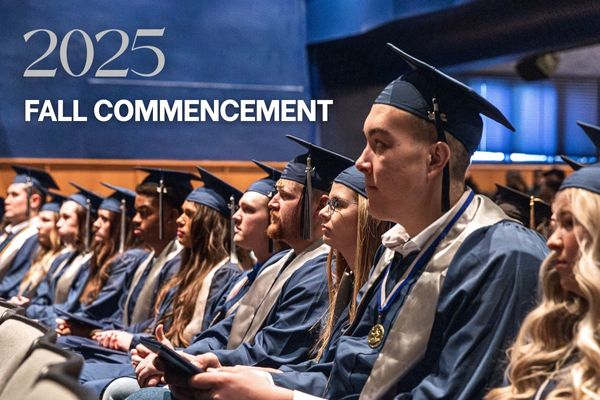 Students sitting in an auditorium in graduation caps